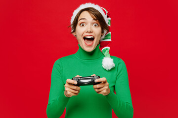 Young gambling woman wear green turtleneck Santa hat posing hold in hand play pc game with joystick...