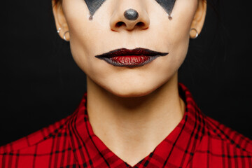 Close up cropped photo shot of young woman with Halloween makeup face art mask wearing clown...