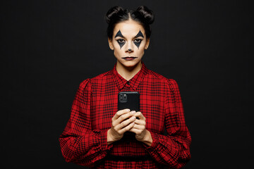 Young serious woman with Halloween makeup face art mask wear clown costume red dress hold use...