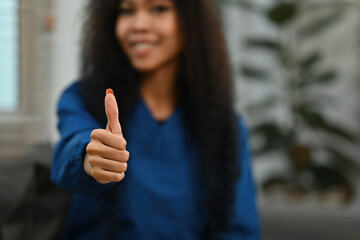 Close Shot of a Happy African Female doctor, caregiver, or nurse giving a thumbs up sign on nursing home background