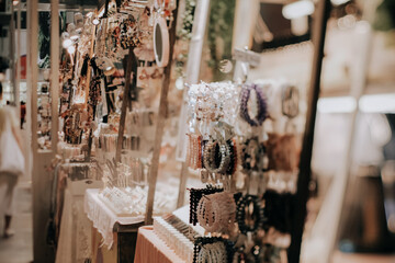 Indoor festive weekend market. Close up of hand made jewellery booth. Social pop up event in shopping mall for entrepreneurs and makers. Captured with tilt-shift lens. Selective focus; bokeh effect