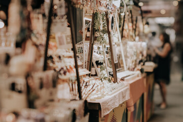 Indoor festive weekend market. Social pop up event of entrepreneurs and makers selling their goods at their booths in shopping mall. Captured with a tilt-shift lens. Selective focus; bokeh effect - obrazy, fototapety, plakaty