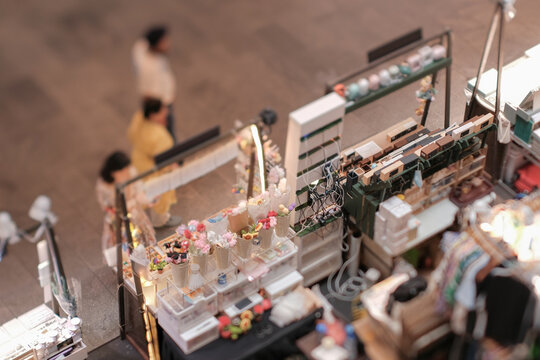 High angle view of customers at indoor festive weekend market. Social pop up event in shopping mall for entrepreneurs and makers. Captured with a tilt-shift lens. Selective focus; bokeh effect