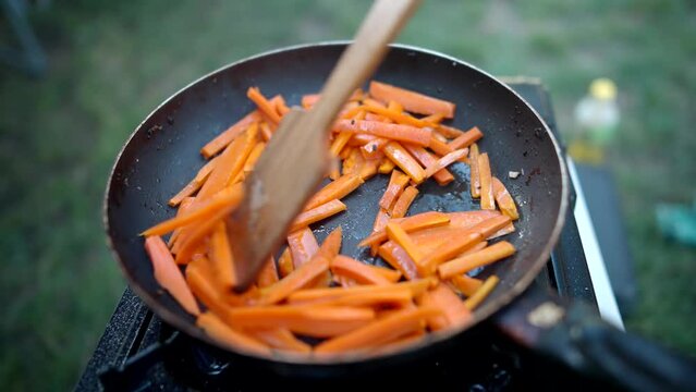 Scarlet carrot sizzling and searing in heated skillet