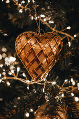 Christmas tree decorated with golden heart toy. Fairy details, bokeh lights, festive winter holiday...