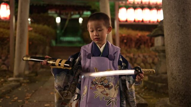 夜の七五三 神社で刀を抜刀する三歳男児