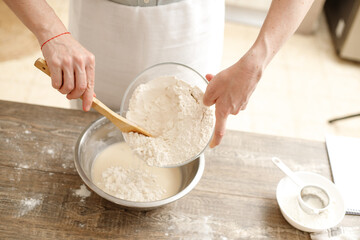 Young man kneading dough on wooden table. Males hands making bread on the kitchen. Baking concept.