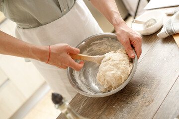 Young man kneading dough on wooden table. Males hands making bread on the kitchen. Baking concept.