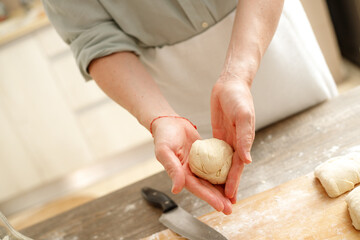 Young man kneading dough on wooden table. Males hands making bread on the kitchen. Baking concept.