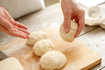 Young man kneading dough on wooden table. Males hands making bread on the kitchen. Baking concept.