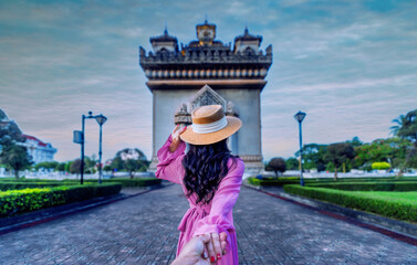 Asian girl in pink dress visits Patuxai at sunset in Vientiane, Lao PDR. - 661893616