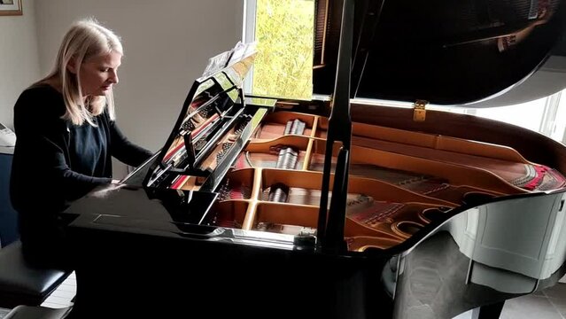 Woman playing a Grand Piano and singing with feeling,while practicing and rehearsing at home,England,UK.