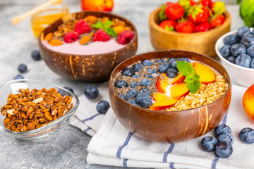 Bowl of granola with yogurt and fresh berries on a texture table. Yogurt berries, acai bowl, spirulina bowl. Healthy food, balanced breakfast. Strawberries, blueberries, kiwi, peach, almonds and chia.