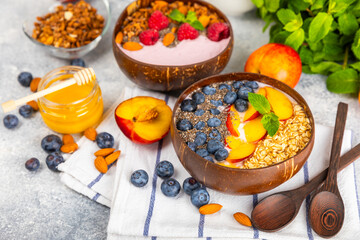 Bowl of granola with yogurt and fresh berries on a texture table. Yogurt berries, acai bowl, spirulina bowl. Healthy food, balanced breakfast. Strawberries, blueberries, kiwi, peach, almonds and chia.