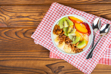 Bowl of granola with yogurt and fresh berries on a texture table. Yogurt berries, acai bowl, spirulina bowl. Healthy food, balanced breakfast. Strawberries, blueberries, kiwi, peach, almonds and chia.