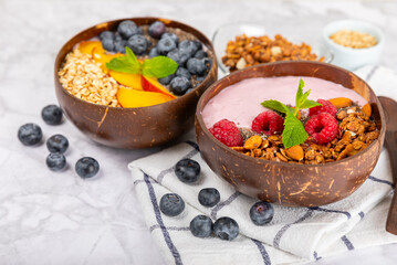 Bowl of granola with yogurt and fresh berries on a texture table. Yogurt berries, acai bowl, spirulina bowl. Healthy food, balanced breakfast. Strawberries, blueberries, kiwi, peach, almonds and chia.