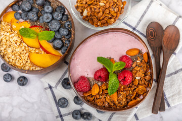 Bowl of granola with yogurt and fresh berries on a texture table. Yogurt berries, acai bowl, spirulina bowl. Healthy food, balanced breakfast. Strawberries, blueberries, kiwi, peach, almonds and chia.