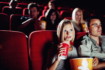 Seat, popcorn and a couple in the cinema watching a movie for entertainment while on a date. Love, food or romance and young people in a theater audience to experience a film together with a drink