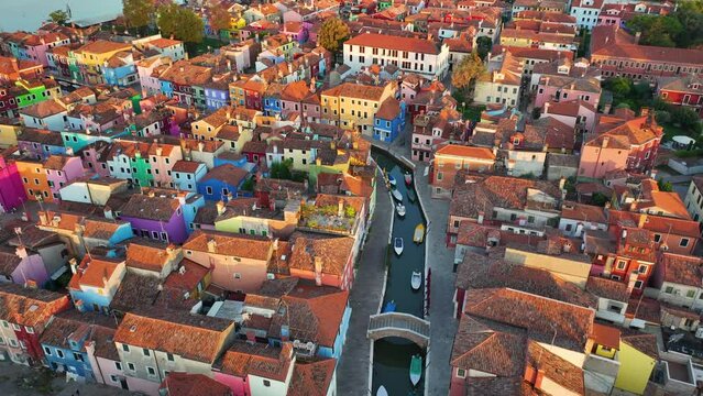 Aerial view of Burano colorful houses, along the Fondamenta embankment, featuring fishing boats and bridges, in the Venice province of the Veneto region, Italy at sunrise golden hour