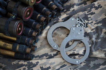 Ukrainian army machine gun belt shells and handcuffs on military uniform. Concept of bribery and...