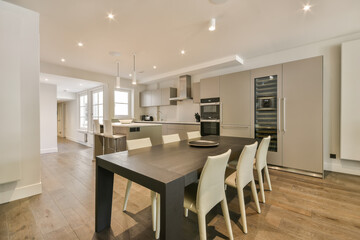 a kitchen and dining area in a modern apartment with wood flooring, white walls and light fixtures...