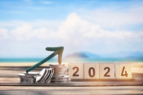 New year 2024 on wooden cube and stack of coins with arrow upwards on planks on tropical beach background. Business beginning with success and return on investment idea