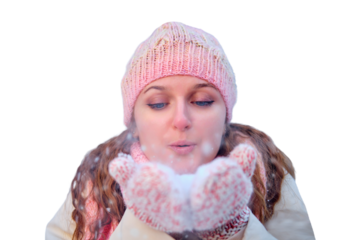 A woman blows snow off her hands in a winter forest on day, isolated on a white background. Pink mittens and hearts as baubles