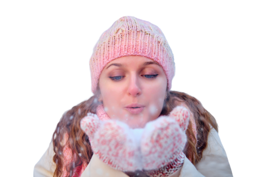 A woman blows snow off her hands in a winter forest on day, isolated on a white background. Pink mittens and hearts as baubles