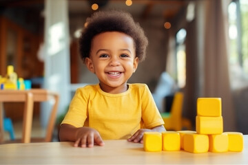 Cute curly African American todler child plays with wooden construction blocks at the table in modern children's room. Concept of games, activities, education of young preschool children - obrazy, fototapety, plakaty