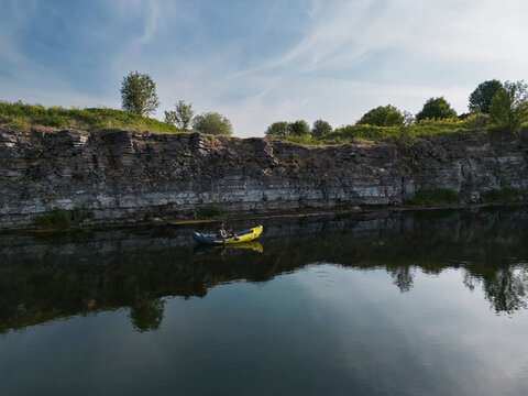 A man is kayaking on the sea, near a cliff, photo from a drone.