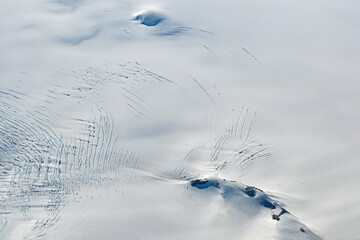 Aerial view of mountains, snow fields, crevasses and glaciers of southern Greenland from airplane window on clear sunny autumn day. © Francisco
