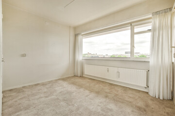 an empty room with white walls and beige carpet on the floor, there is a window that looks out to the city