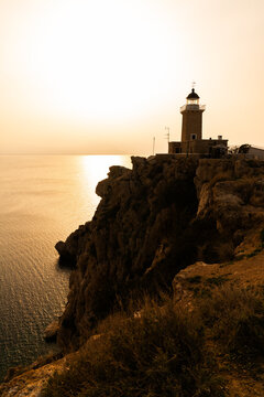 Limni Vouliagmenis, Greece - 1 March 2023 - the  Lighthouse Melagavi on the farest point at the Corinth channel at sunset
