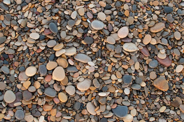 Pebbles of different colors on the beach in the port of Sagunto, Spain. Amazing pebbles background. Pebbles texture.