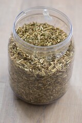 A portrait of a plastic jar or pot full of dried loose fresh viola tricolor leaves to set a fresh cup of tea. The herbs are ready to be used in a relaxing warm beverage for some zen time.
