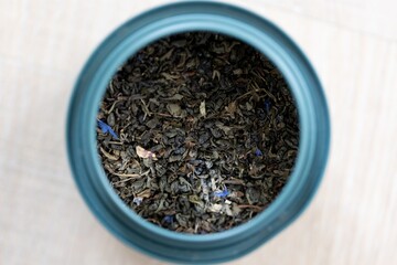 A close up portrait of loose dried fresh marrakech mint tea in a blue can. Ready to be used to make a delicious fresh cup of the warm beverage for some soothing relaxation and zen time.