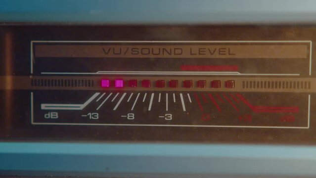 Analog VU meter with light indicator showing sound level on cassette deck. Close-up view, zoom-out shot