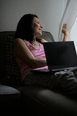 Happy adult woman looking at the window with a laptop.
