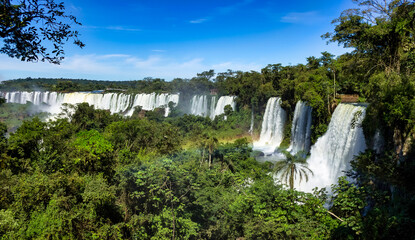 Panorama of Iguazu (Iguacu) waterfall, amazing cascade waterfalls landscape in Argentina. Majestic powerful natural waterfalls, summer sunny day, rainbow. World nature concept. Copy ad text space