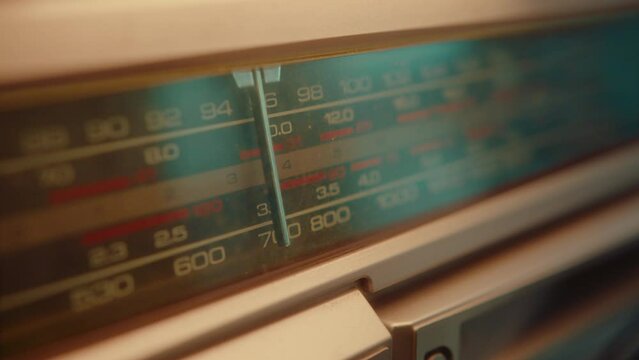 Vintage radio dial with moving arrow running through frequencies and searching a channel. Close-up shot