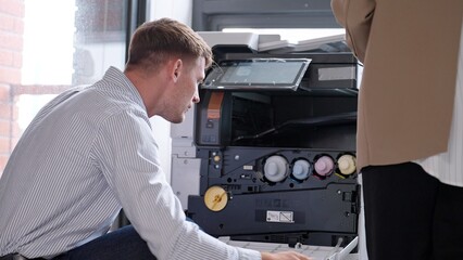 Photocopier or printer has error. Young businessman checking a photocopier machine in office. Caucasian man worker is sitting beside error copy machine at the office