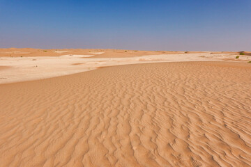 Panorama of the Rub Al Khali desert with red zig-zag sand and white limestone formations.