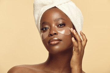 Beautiful Afro-american woman applying under eye patches.