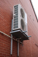 Air conditioner unit installed outside on a brick wall