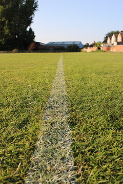White painted line on a local park grass playing field used to mark the football pitch area
