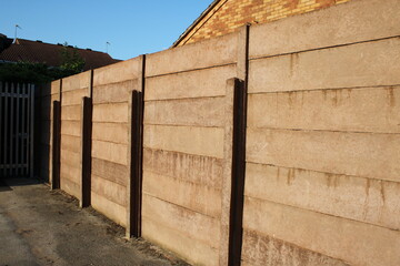 Concrete fence, made of concrete posts with stacked gravel boards blue sky background UK