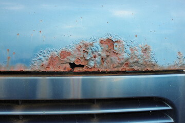Close up of penetrating rust on a blue bonnet from an old disused car