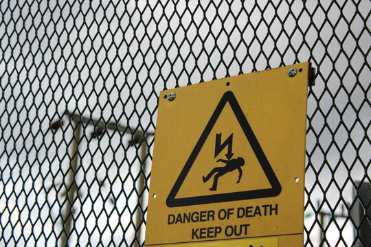 Danger of death sign taken at an electrical substation with overhead pylon in background abstract
