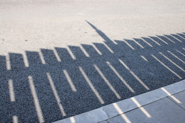 Fototapeta premium Detailed shadow of wooden fence on pavement and asphalt road