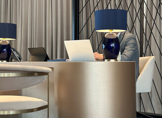 Man in suit working on laptop at the table in lounge, reception, lobby, hall, foyer or office space.